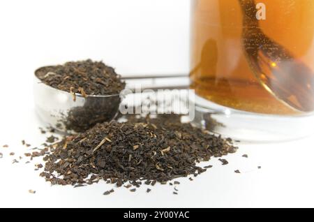 Foglie di tè nel misurino e un bicchiere di tè. Tealeaves nel misurino e un bicchiere di tè Foto Stock