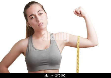 Potente donna misurando il suo bicipite con un giallo nastro di misurazione Foto Stock