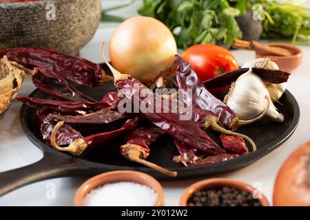 Una vista di peperoncini di guajillo essiccati su una comal, tra gli altri ingredienti di salsa. Foto Stock