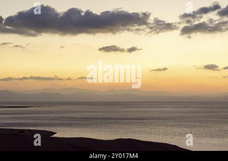 Paesaggio all'alba costa del Mar Rosso con la silhouette di alte montagne e cielo con nuvole Foto Stock