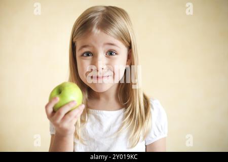 Portreit poco divertente ragazza bionda con mela verde Foto Stock