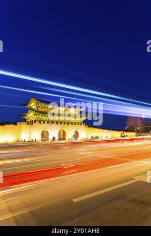 Colorate strisce di luce dai semafori sul traffico in movimento di fronte allo storico Palazzo Gyeongbokgung, cancello d'ingresso di Gwanghwamun al crepuscolo nel centro cittadino Foto Stock