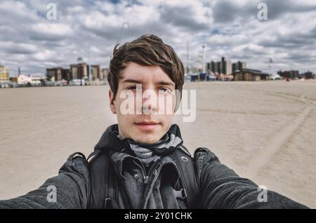 Giovane uomo adulto con capelli marroni e barba che prende un selfie di fronte a coney Island, brooklyn New york, stanchezza a causa di jetlag, america Foto Stock