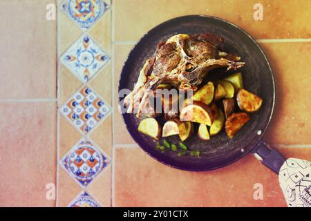 Brasati di carne di capra con salsa di pomodoro e patate arrosto in padella. Vista superiore Foto Stock