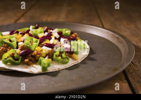 Tortilla messicana con carne, fagioli rossi, peperoncino jalapeno e cipolla su un tagliere Foto Stock