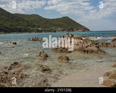 Rocce su un tranquillo tratto di costa con acqua e cielo turchesi, Corsica, Mar Mediterraneo, Francia, Europa Foto Stock