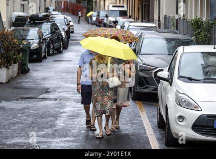 Persone con ombrelloni attraversano una strada a Diana Marina, Italia, 18/08/2024, Diano Marina, Liguria, Italia, Europa Foto Stock