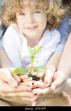 Famiglia che tiene il giovane albero verde in primavera. Concetto di ecologia Foto Stock