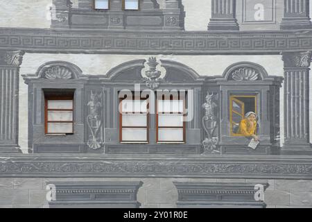 Muro della casa con finestra e pittura di illusione grigia, ornamenti, sgraffiti e decorazioni, pittura di illusione, donna che si appoggia fuori dalla finestra, guarda, Foto Stock