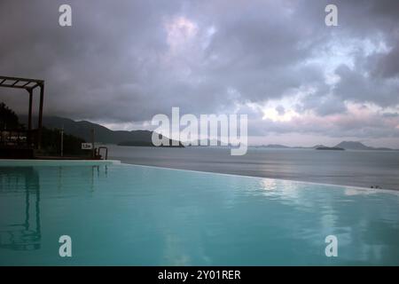 Dolsan-eup, Yeosu-si, Corea del Sud - 26 luglio 2024: Giovane donna che guarda l'alba in un resort con piscina affacciata sul mare di Yeosu Foto Stock