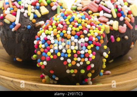 Messa a fuoco selettiva su dolci dolci al cioccolato tortina farcita con granelli colorati in un piatto di legno Foto Stock