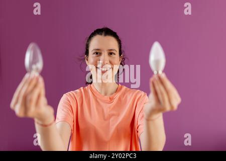 Confronto tra lampadine economiche e normali. Concetto di vita ecologica e sostenibilità - donna sorridente che confronta la lampadina a risparmio energetico con quella a incandescenza Foto Stock