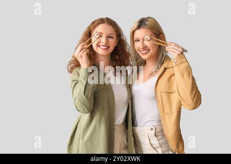 Giovani donne con sushi roll su sfondo chiaro Foto Stock