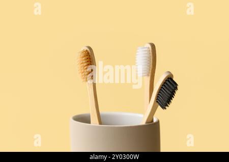 Spazzole da denti in bambù in supporto su sfondo beige Foto Stock