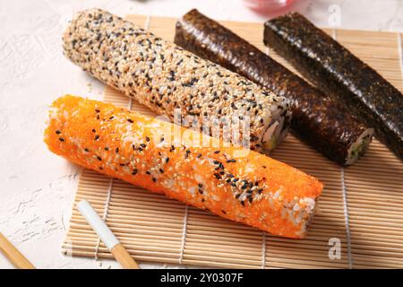 Gustosi panini di sushi e tappetino di bambù su sfondo chiaro Foto Stock