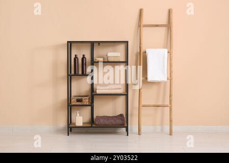 Scaffale con asciugamano e accessori da bagno vicino alla parete beige Foto Stock