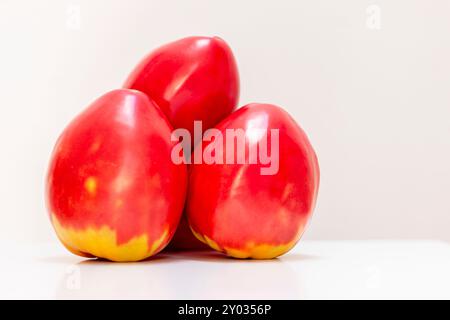 Pomodori con cuore di OX isolati su sfondo bianco. Pomodori rossi maturi in una scatola di plastica verde. Un prodotto ecologico. Verdure coltivate in Foto Stock