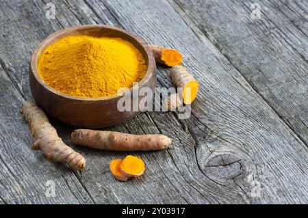 Polvere di curcuma in cucchiaio o ciotola e radice di curcuma fresca su fondo di legno, concetto di spezie, ( curcuma longa ) Foto Stock