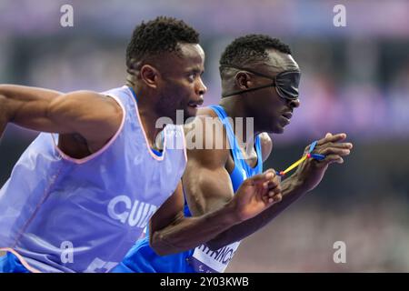 Parigi, Francia. 31 agosto 2021. Guillaume Junior Atangana (R) e la sua guida Donard Ndim Nyamjua del Refugee Paralympic Team (RPT) gareggiano durante la semifinale maschile 400m T11 di para atletica ai Giochi Paralimpici di Parigi 2024, Francia, 31 agosto 2021. Durante i Giochi Paralimpici di Parigi 2024, otto atleti e un corridore guida competono come parte della più grande squadra Paralimpica per i rifugiati di sempre. Crediti: Zhang Cheng/Xinhua/Alamy Live News Foto Stock