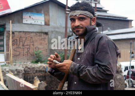 Un tipico lavoratore controlla il suo cellulare per le strade di Srinagar, in India Foto Stock