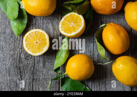 Frutti di limone giallo maturi freschi con foglie su fondo di legno Foto Stock