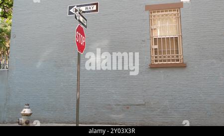 Incrocio di New York City, incrocio di Minetta Street, freccia a senso unico. Edificio residenziale Manhattan Greenwich Village, New York, Stati Uniti. Muro di mattoni blu, finestra, segnale di stop rosso Foto Stock