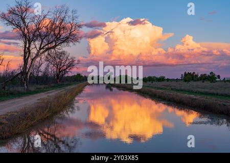 Una grande nube di tempesta colorata si riflette in un canale di irrigazione a St. George nel Queensland meridionale, Australia Foto Stock