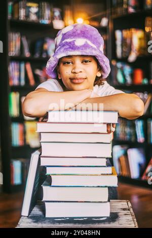 Ritratto di una giovane donna appoggiata su una pila di libri in libreria Foto Stock