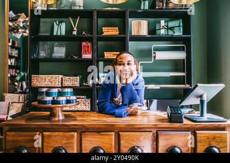 Ritratto di una donna sorridente appoggiata al gomito sopra il tavolo in negozio Foto Stock