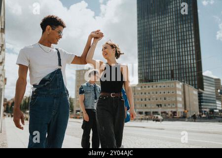 Giovane alla moda che balla con un'amica mentre cammina per strada in città Foto Stock