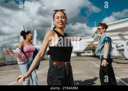 Ritratto di una bella giovane donna in un ambiente informale che danzava con amici maschi e femmine nel parcheggio sotto il cielo nuvoloso Foto Stock