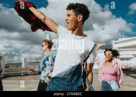 Allegro hipster in tuta bavaglino che ballano con amici maschi e femmine nel parcheggio Foto Stock