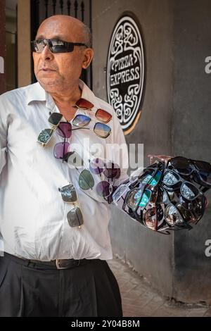 Venditore di occhiali da sole, venditori di occhiali, acquirenti di occhiali caldi, protezione per gli occhi, dal sole e dalla polvere. Uomo anziano che vende occhiali da sole in una strada di Mumbai India-ma Foto Stock