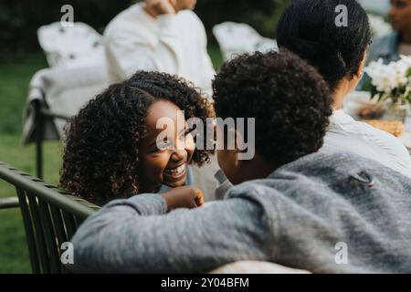 Ragazza felice che parla con un amico maschio durante la cena in giardino Foto Stock