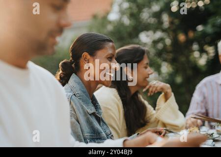 Donna matura felice che pranza con i membri della famiglia durante la riunione sociale Foto Stock