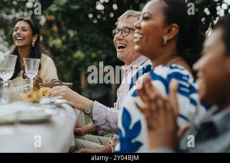 Buon anziano che si diverte con i membri della famiglia a pranzo e festa Foto Stock
