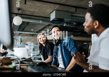 Programmatori di computer di sesso maschile e femminile che parlano con un collega seduto in ufficio Foto Stock