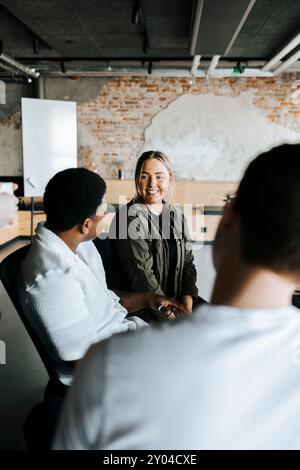 Programmatore donna che parla con colleghi uomini in ufficio Foto Stock