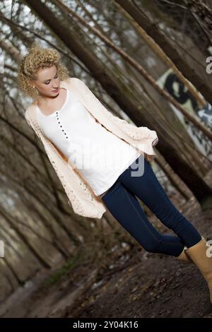 Giovane donna bionda con lunghi capelli ricci in un ambiente autunnale all'aperto Foto Stock