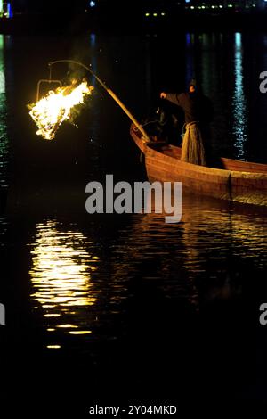 Inuyama, Giappone, 5 luglio 2015: Un uccello su una tradizionale barca di legno si prepara ad eseguire la pesca dei cormorani ukai con fiamme notturne sul fiume Kiso a Gifu pre Foto Stock