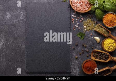 Spezie ed erbe su fondo di pietra nera. Vista dall'alto con spazio libero per menu o ricette Foto Stock