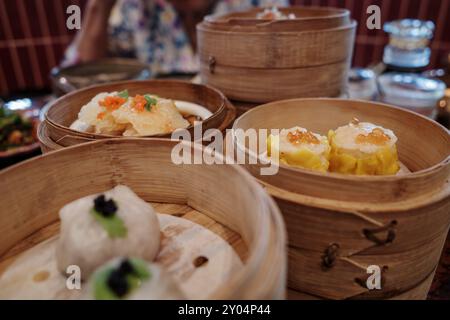 Vista ravvicinata di una varietà di piatti dim sum serviti in tradizionali vapori di bambù. Foto Stock