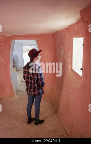 Donna che guarda la finestra all'interno delle grotte di Argueda con pareti rosa, in Spagna Foto Stock