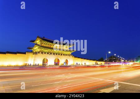 Lunga esposizione che strizza le luci di coda delle auto lasciando il semaforo di fronte al cancello principale di Gwanghwamun per il Palazzo Gyeongbokgung al crepuscolo nel centro cittadino su una clea Foto Stock