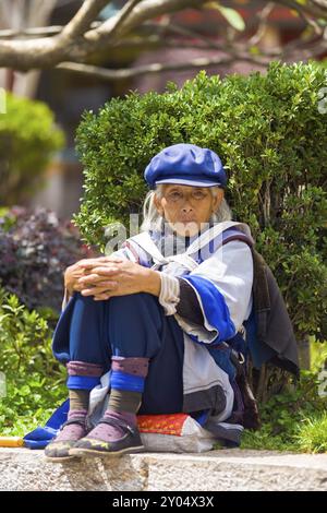 Lijiang, Cina, 30 settembre 2017: Una donna Naxi matura vestita con abiti tradizionali seduta dopo aver ballato nella città vecchia di Lijiang, Yunnan, Cina, Asia Foto Stock