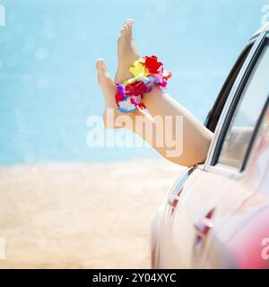 Donna gambe contro il blu del mare e della spiaggia sfondo. Vacanze estive - concetto Foto Stock