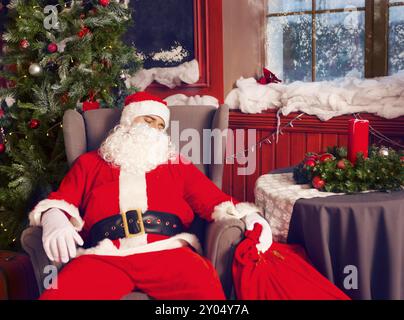 Foto di felice Babbo Natale con big bag di presenta a dormire la poltrona Foto Stock