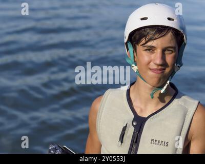 Giovane sportivo con casco e gilet sul lago, ritratto, sport acquatici, sci d'acqua nel wakepark Foto Stock