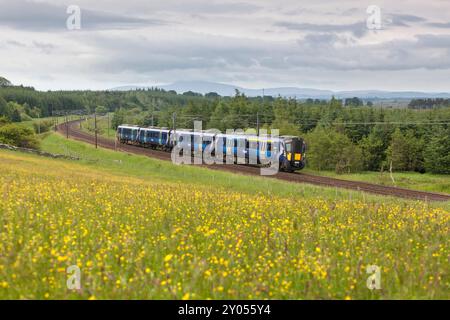 Treno elettrico multiunità ScotRail Siemens classe 385 che passa per la campagna di Auchengray, Scozia, Regno Unito Foto Stock