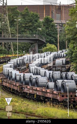 Le bobine di acciaio a nastro, sui carri merci, presso lo stabilimento siderurgico ThyssenKrupp di Schwelgern a Duisburg-Marxloh fa parte della acciaieria Bruckhausen, Renania settentrionale Foto Stock